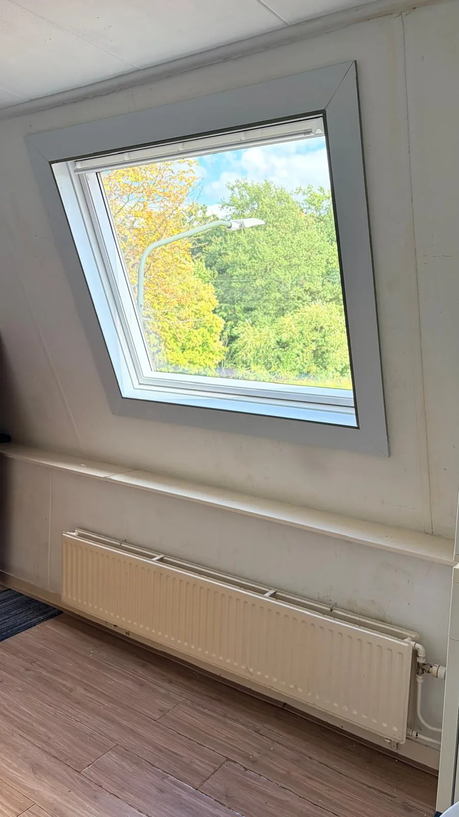 Het nieuwe dakraam van binnenuit gezien, in de schuine wand van de kamer boven een radiator
