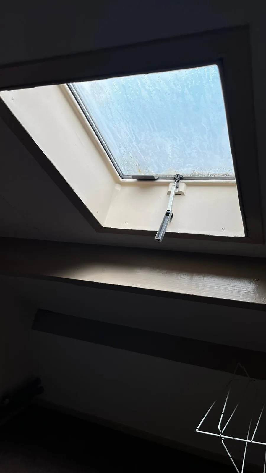 Het oude dakraam op de zolder in Boxtel, met blind geworden glas en een oude uitzetarm