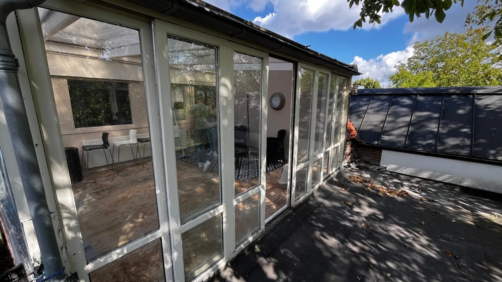 De oude serre in Esch van buiten: witte kozijnen en een dak van polycarbonaatplaten