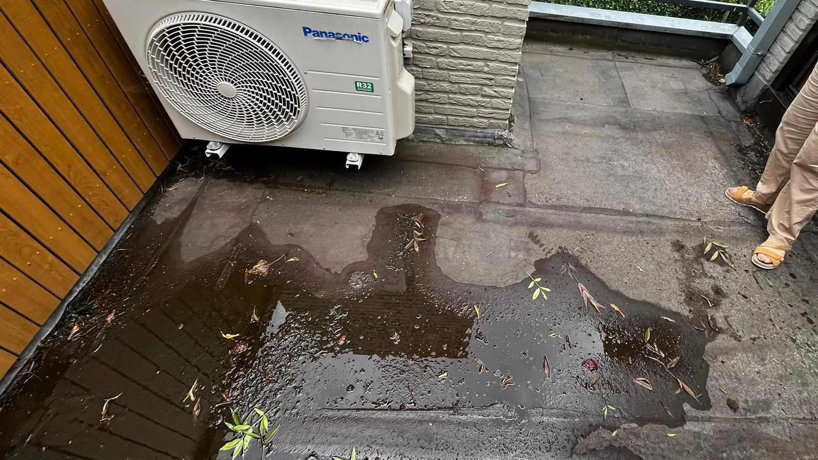 Het kale platte dak in Veghel met plassen en de losse buitenunit van de airco